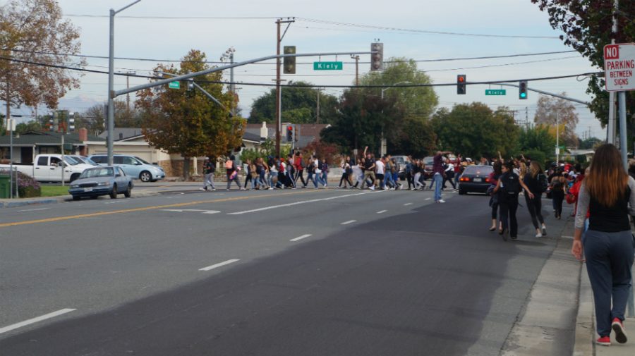 Students cross the street in the school-wide walk out on Thursday.