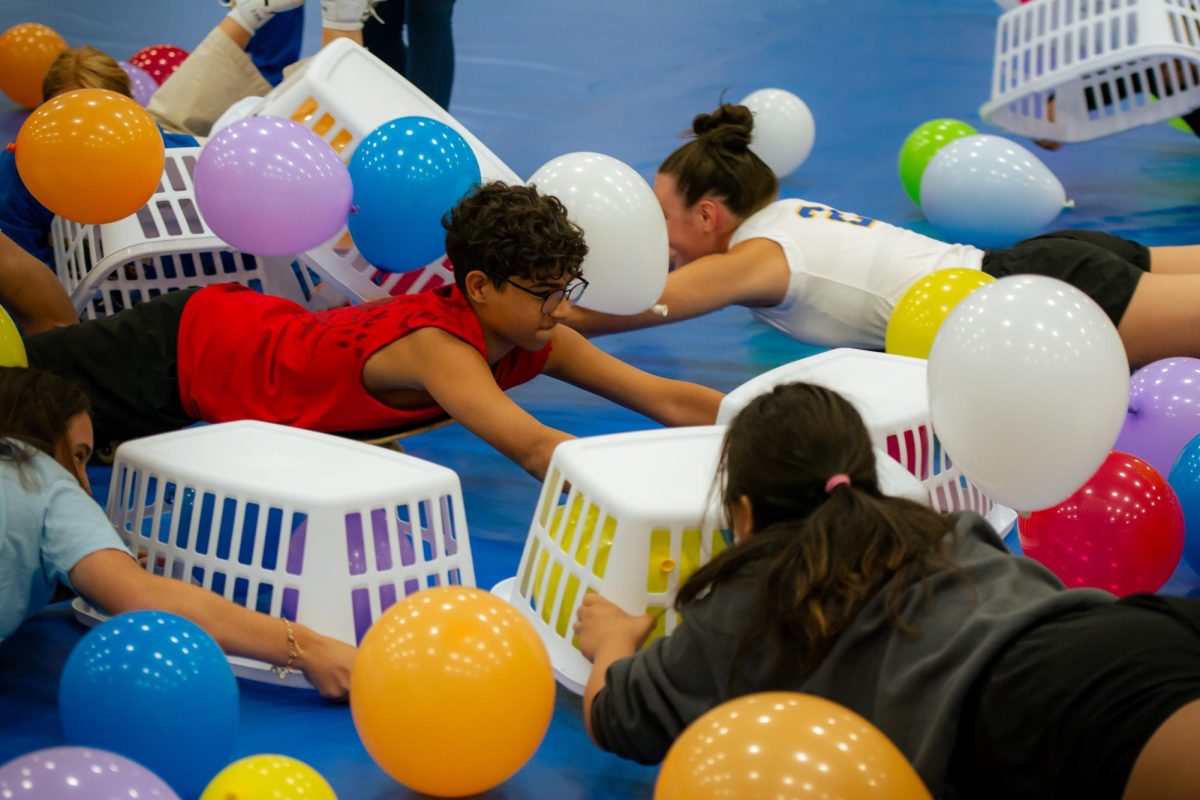 Sophomore Ali Al-hemyari reaches out to grab the balloon with his basket during the Hungry Hungry Hippos game. 