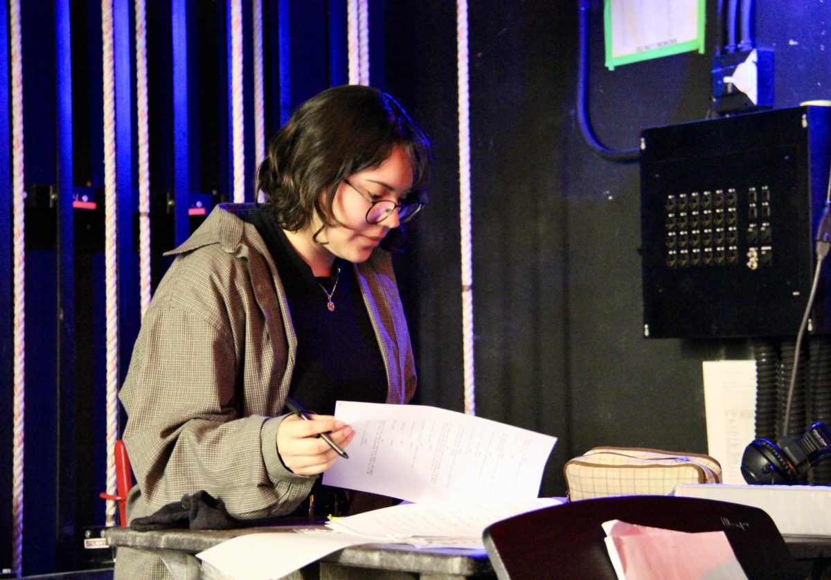 Technical director of the drama department, senior Lorena Ortiz, flips through notes backstage as she prepares for a show.