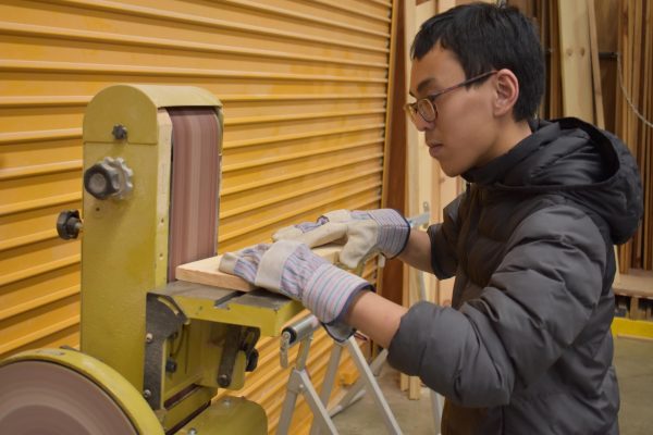 Junior Andrew Nguyen learns how to use a belt sander in his construction class.
