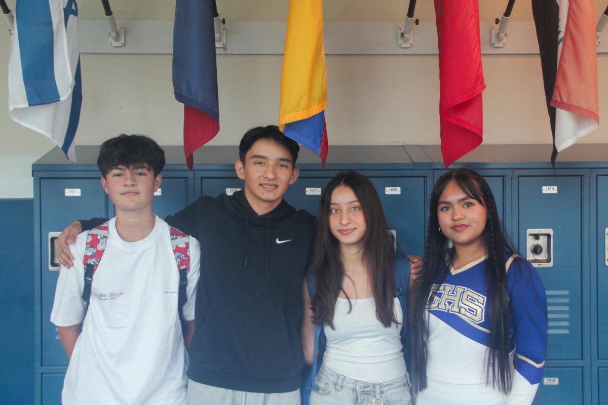 Seniors Sara Calducho (right) and Dylan Sanchez (second to left) stand among fellow Colombians in front of the library’s flag wall.